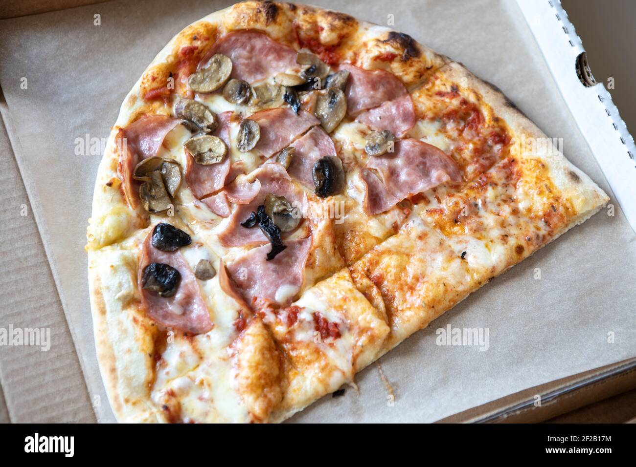 La pizza di famiglia, a metà ovale, è composta da due tipi, margarita, funghi prosciutto. Concetto di consegna di cibo, da asporto, cucina, fast food, togetherness. In alto Foto Stock