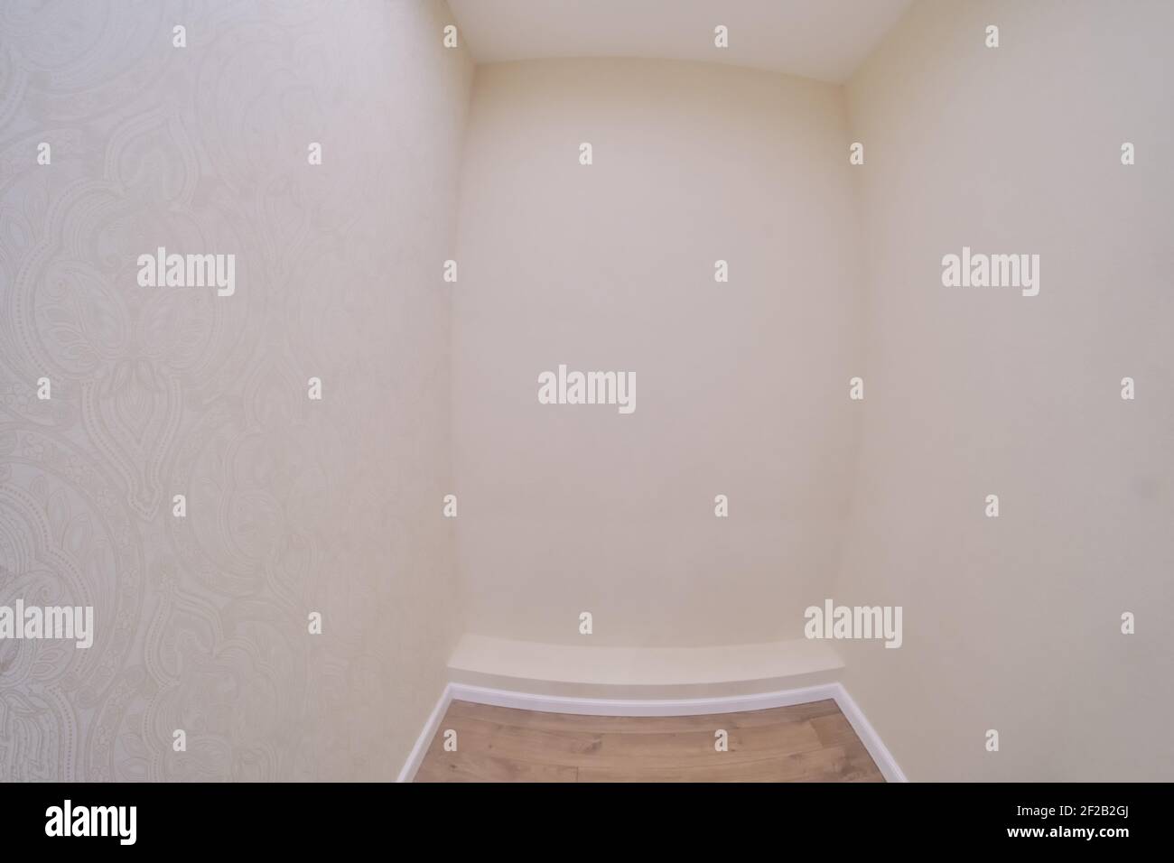 Piccola camera vuota con carta da parati beige, soffitto bianco e pavimento in laminato Foto Stock