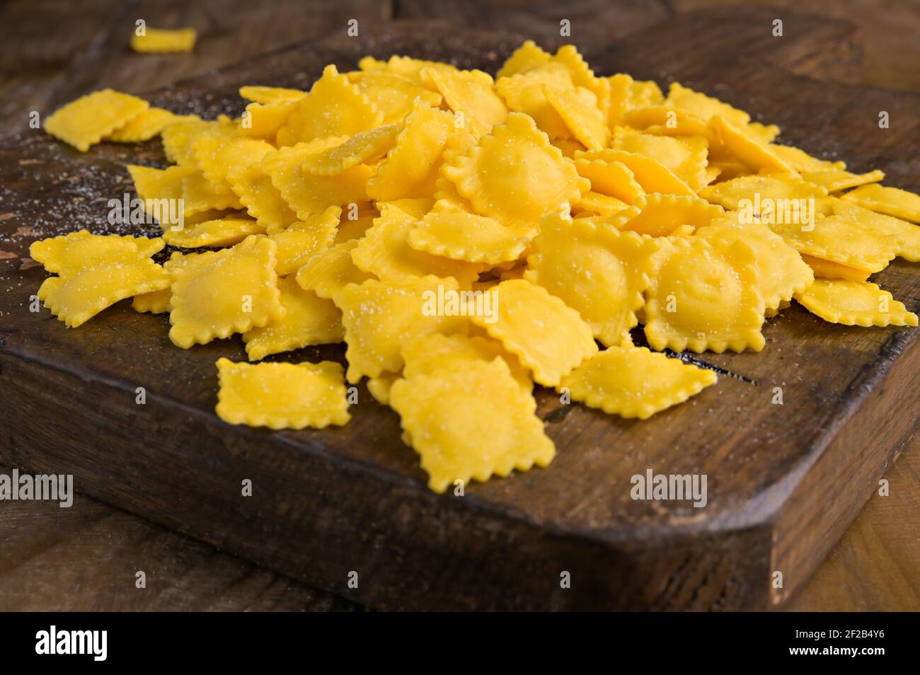 Tartollini al formaggio o alla carne per cucinare in brodo, piatto tradizionale per celebrazioni in italia, regione Emilia Romagna. Pasta fresca fatta in casa con ripieno su un tavolo di legno. Foto Stock