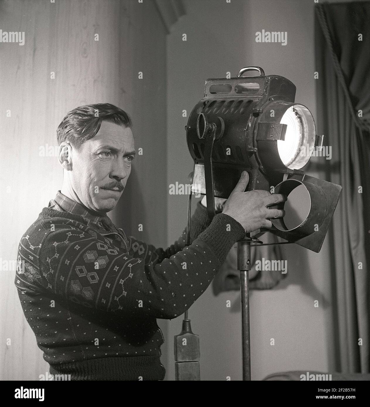 Studio cinematografico negli anni '40. Un uomo che lavora sul set cinematografico gestisce la lampada che viene utilizzata per illuminare la scena del film durante le riprese del film Sjätte budet. Svezia 1947. rif AA6-1 Foto Stock