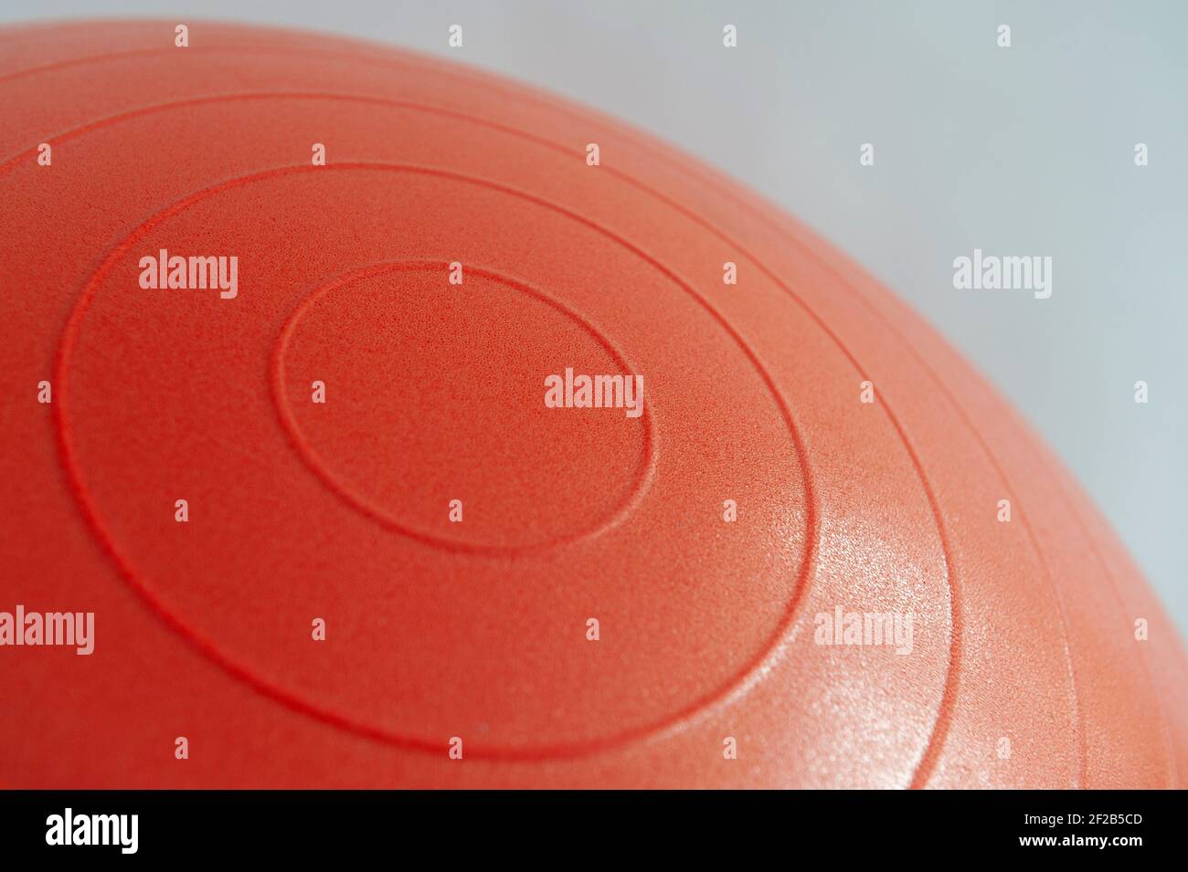 Primo piano dettaglio foto di costolature circolari su una palla da palestra gonfiabile rossa su sfondo bianco. Foto Stock