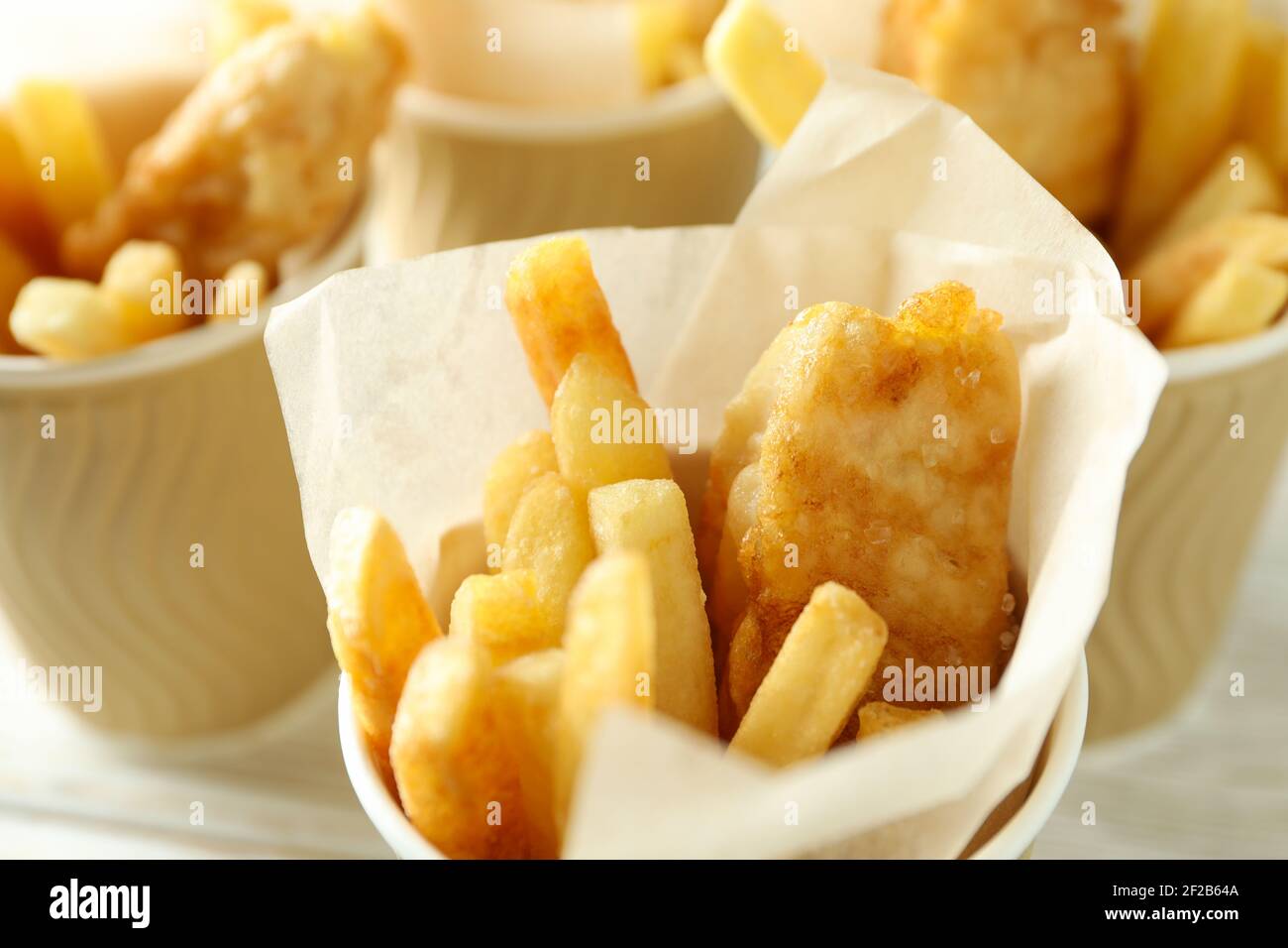 Primo piano di bicchieri di carta con pesce fritto e patatine, pesce impanato dorato e patatine croccanti Foto Stock