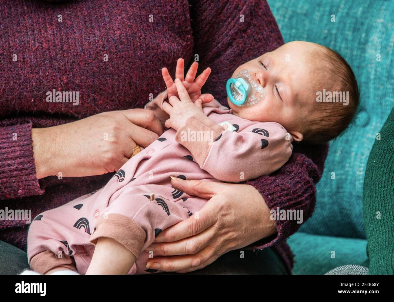Una bambina di due mesi addormentata in braccia di nannies. Foto Stock