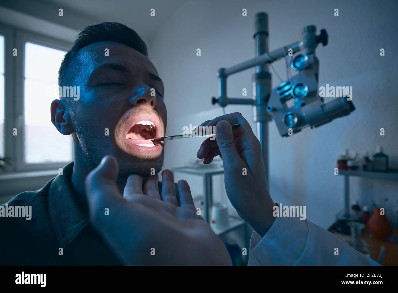 Paziente presso la clinica ENT. Medico specialista - Otolaringologo facendo esame della gola del giovane uomo. Foto Stock