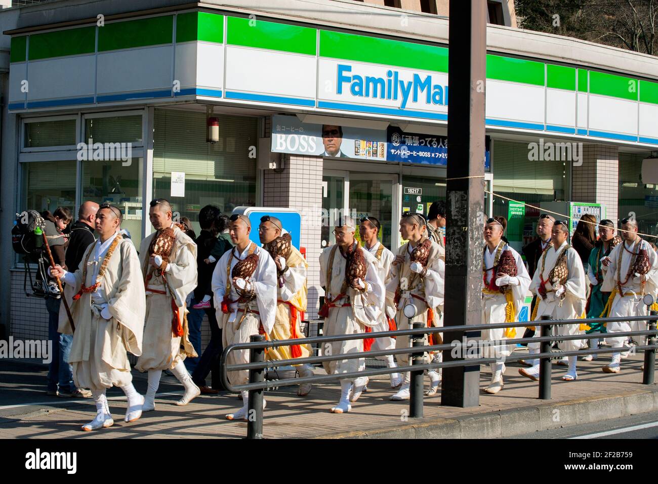 Shugenja/Yamabushi pellegrini che prendono parte al Hirawari Matsuri - Fire Walking Festival passando Family Mart negozio, Monte Takao, Hachioji, Giappone Foto Stock