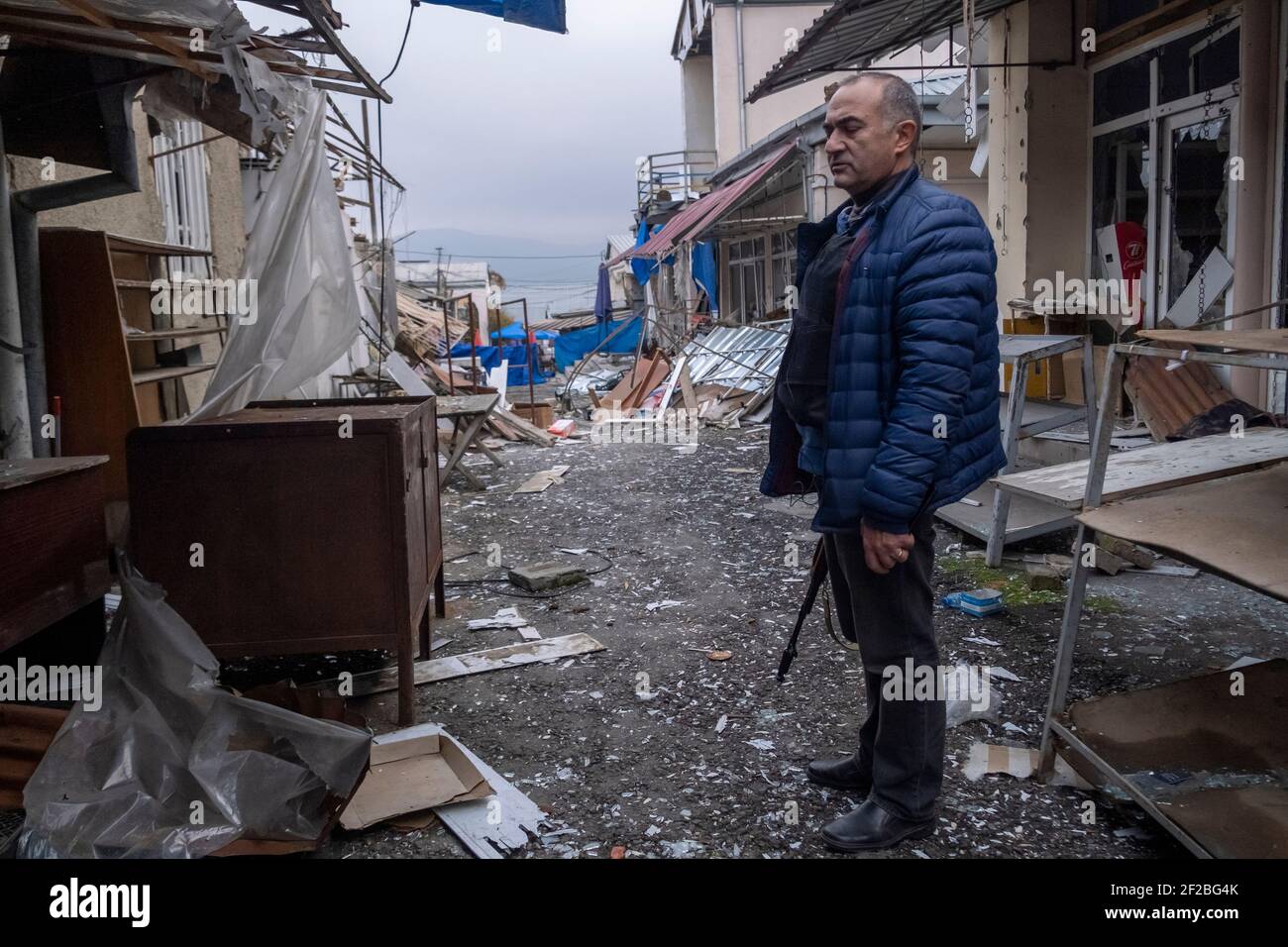 STEPANAKERT, NAGORNO KARABAKH - NOVEMBRE 04: Tevan Poghosyan consigliere del presidente armeno ed ex-membro del Parlamento armeno si trova armato di AK-47 Kalashnikov fucile tra le rovine del mercato centrale colpito da un attacco di zelo azero su Stepanakert, capitale de facto dell'autoproclamata Repubblica di Artsakh o Nagorno-Karabakh, De jure parte della Repubblica di Azerbaigian il 04 novembre 2020. I combattimenti tra Armenia e Azerbaigian sul Nagorno-Karabakh, noto anche come Repubblica Artsakh, sono riesplose alla fine di settembre in una guerra di sei settimane con entrambi i paesi che si accusano l'un l'altro Foto Stock