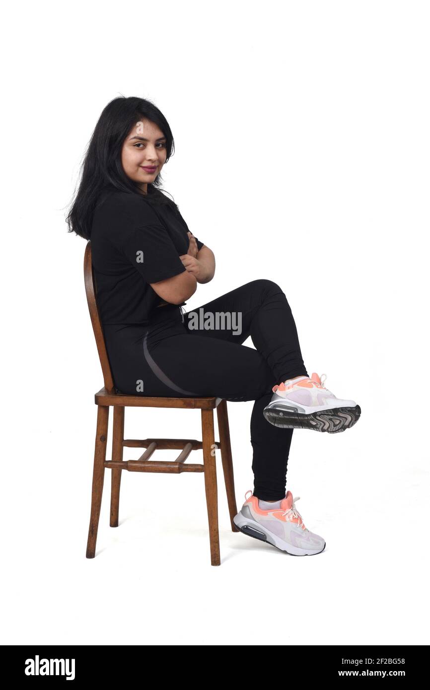 Donna latina che indossa abiti sportivi seduti lateralmente e gambe  incrociate su sfondo bianco Foto stock - Alamy