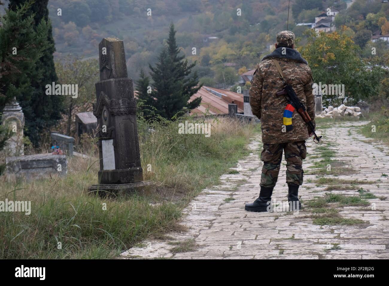 GISHI, NAGORNO KARABAKH - NOVEMBRE 05: Un soldato dell'esercito di difesa Artsakh porta dietro la schiena un fucile d'assalto Kalashnikov mentre si trova in un cimitero nel villaggio di Kish o Gishi nella provincia di Martuni dell'autoproclamata Repubblica di Artsakh o Nagorno-Karabakh, De jure parte della Repubblica di Azerbaigian il 05 novembre 2020. I combattimenti tra Armenia e Azerbaigian sul Nagorno-Karabakh, noto anche come Repubblica Artsakh, sono riesplose alla fine di settembre in una guerra di sei settimane con entrambi i paesi accusandosi reciprocamente di provocazioni che hanno lasciato migliaia di morti. Foto Stock