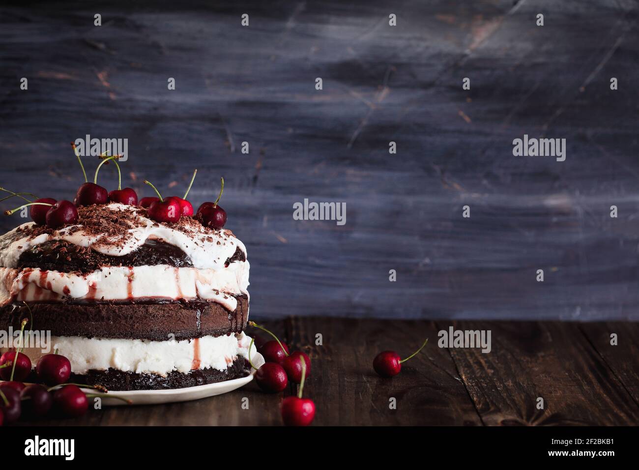 Deliziosa torta alla ciliegia della Foresta Nera, dessert a torta Schwarzwald, su un tavolo di legno rustico scuro. Messa a fuoco selettiva con sfondo sfocato e spazio libero per Foto Stock
