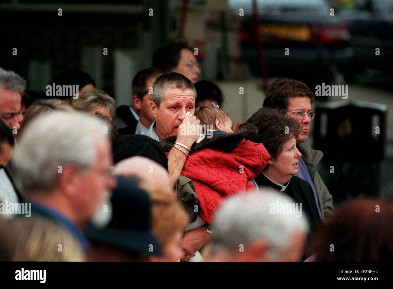 Incidente ferroviario di Paddington ottobre 1999A uomo che tiene un bambino uno dei molti membri del pubblico che si sono uniti agli amici e famiglia al servizio memoriale della ferrovia di paddington Crash si è tenuto sulla corte anteriore del sainsbury's distributore di benzina vicino al sito dell'incidente Foto Stock