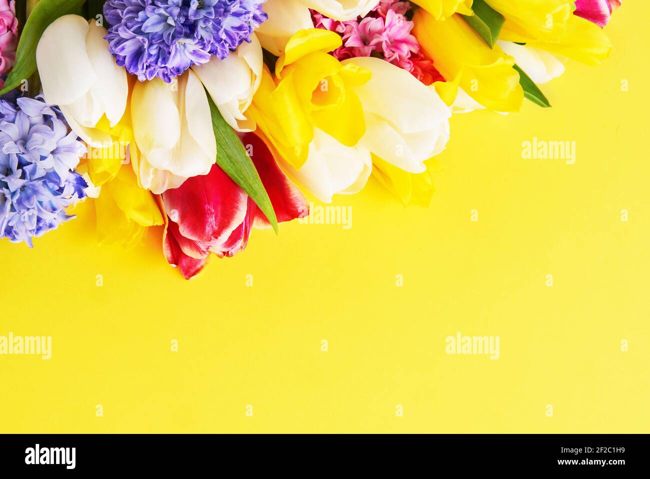 Bouquet di fiori primaverili su sfondo giallo. Festa della mamma, giorno di San Valentino, concetto di celebrazione del compleanno. Vista dall'alto, spazio di copia per il testo. Foto Stock