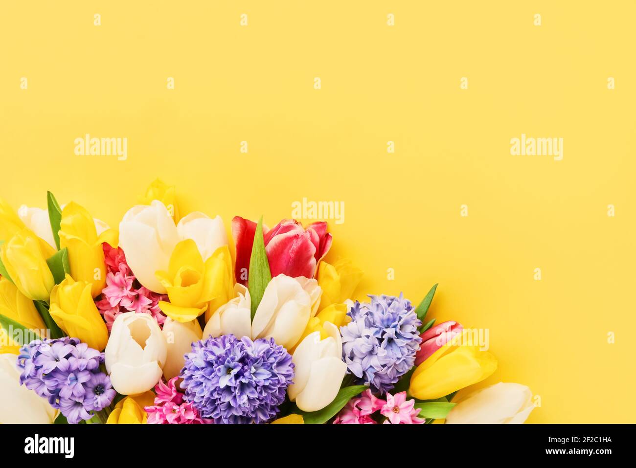 Bouquet di fiori primaverili su sfondo giallo. Festa della mamma, giorno di San Valentino, concetto di celebrazione del compleanno. Vista dall'alto, spazio di copia per il testo. Foto Stock
