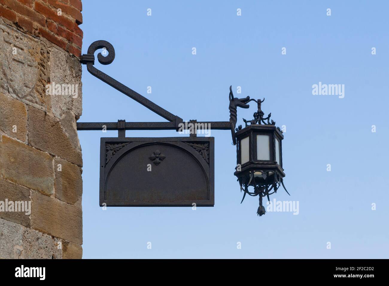 Cartello nero in metallo vecchio stile con lanterna appesa l'angolo di un muro di pietra Foto Stock