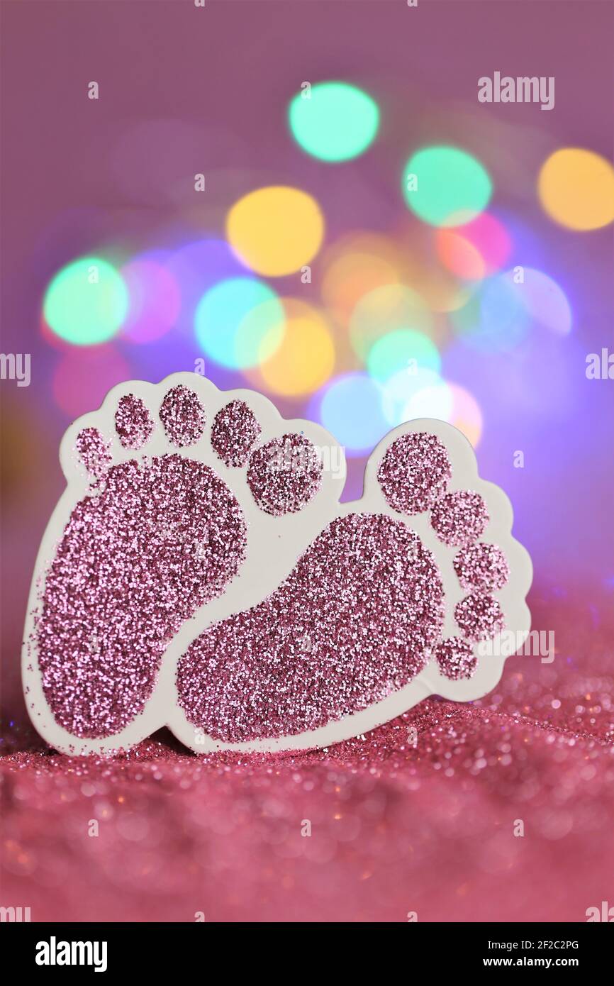 Neonato card. La nascita di una ragazza. Piedini decorativi del bambino di glitter rosa su sfondo di glitter rosa con bokeh.Baby giallo multicolore di illuminazione invito Foto Stock