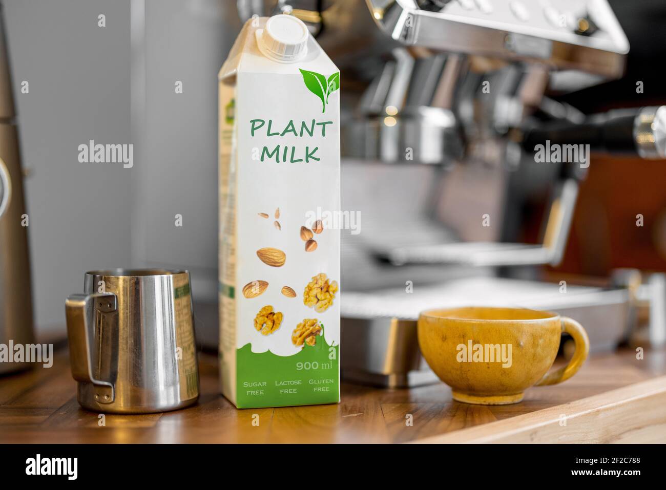 Confezionamento del latte vegetale vicino al sminuetto, una tazza di caffè  e macchina da caffè su un tavolo di legno in cucina. Latticini biologici,  bevanda alternativa Foto stock - Alamy