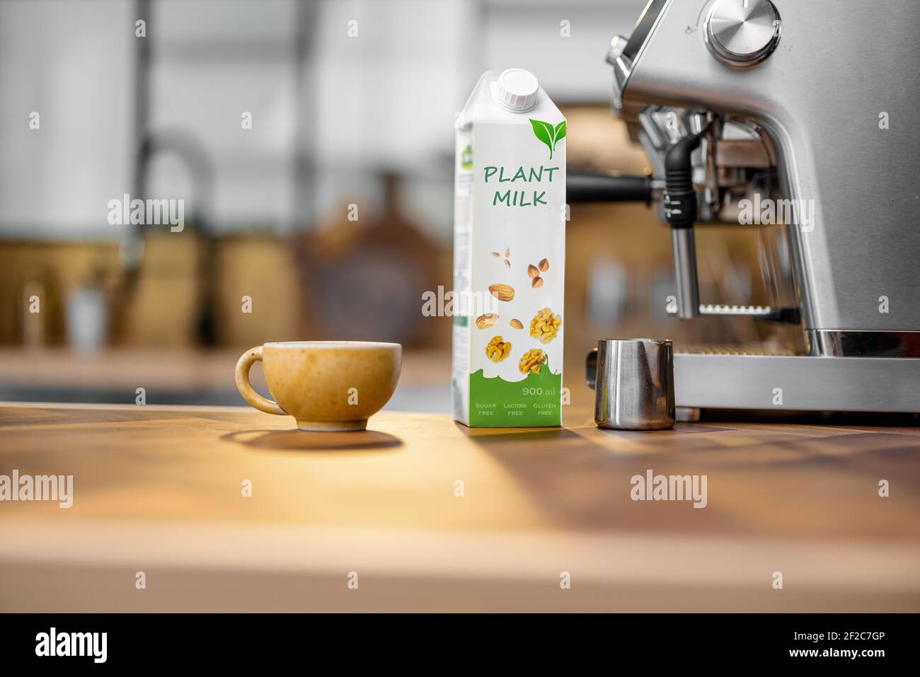 Confezionamento del latte vegetale vicino a una tazza di caffè, una macchina da caffè e una macchina da caffè su un tavolo di legno in cucina. Latticini biologici, bevanda alternativa. Spazio di copia. Foto Stock