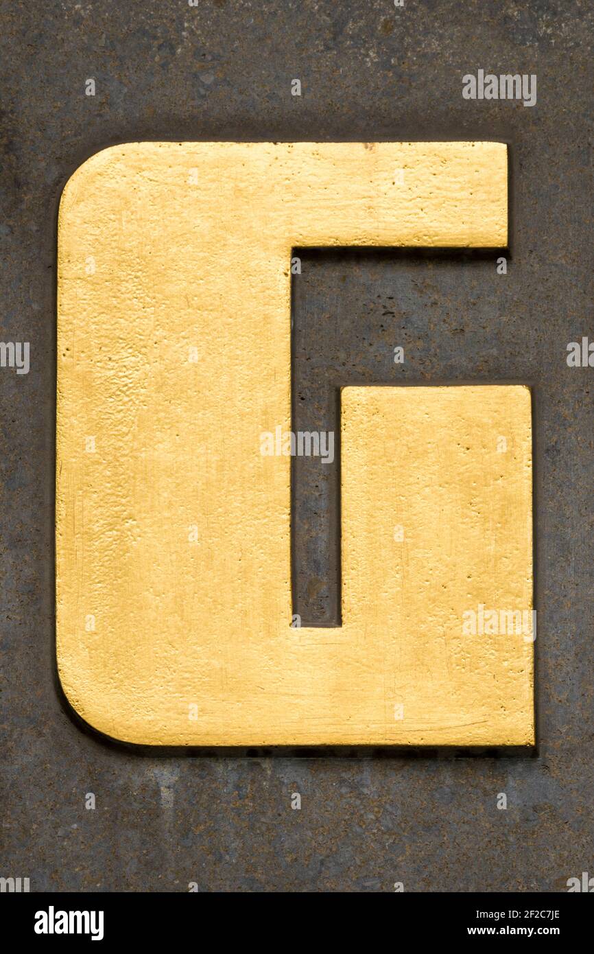 Lettera d'oro G su una parete marrone Foto Stock