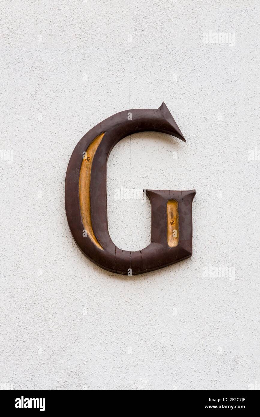 Lettera G di legno marrone con linee decorative dorate Foto Stock