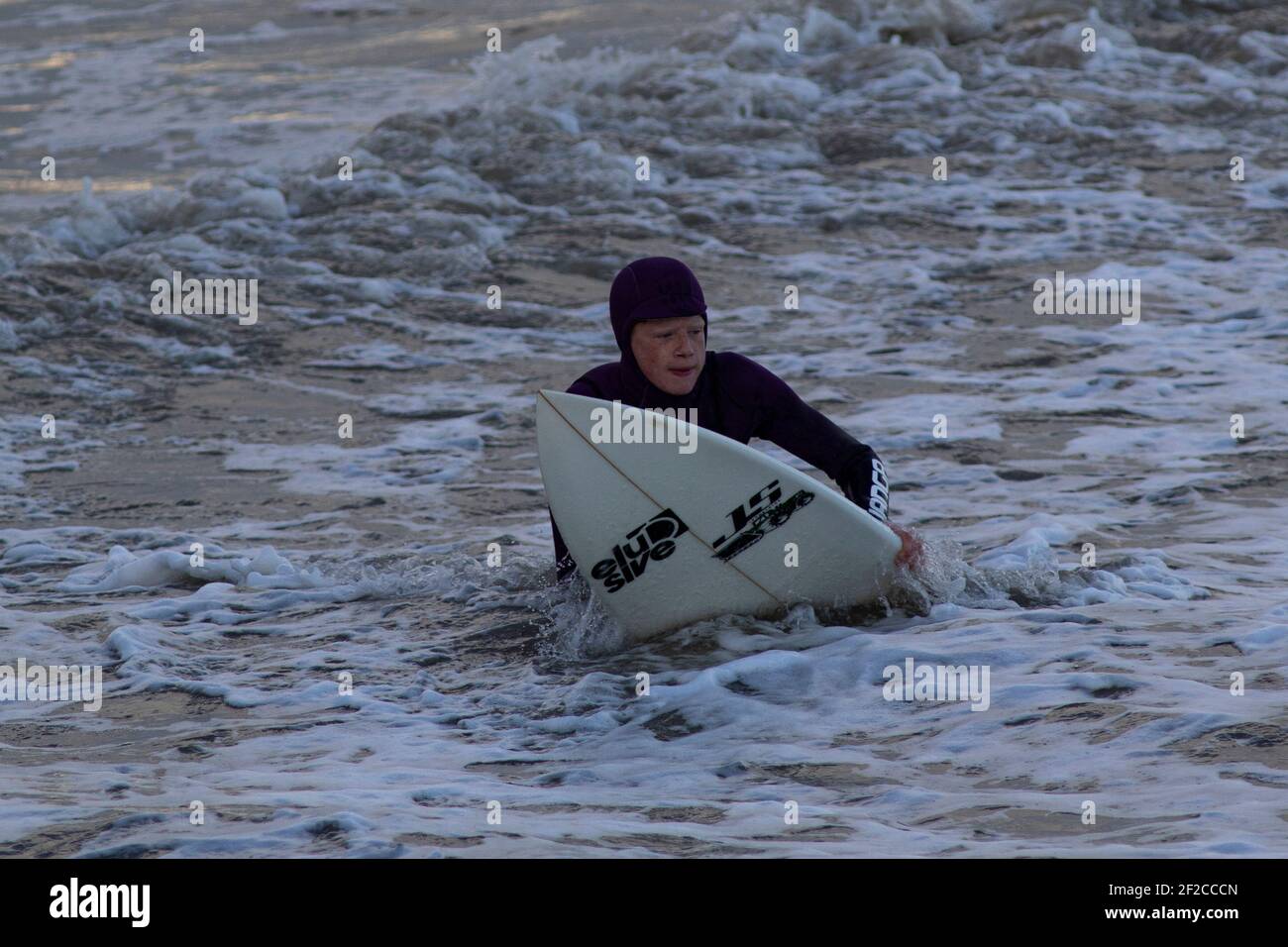 Un surfista a Coney Beach, Porthcawl durante l'alta marea e forti venti di 67mph che colpiscono la costa del Galles del Sud l'11 marzo 2021. Credito: Lewis Mitc Foto Stock