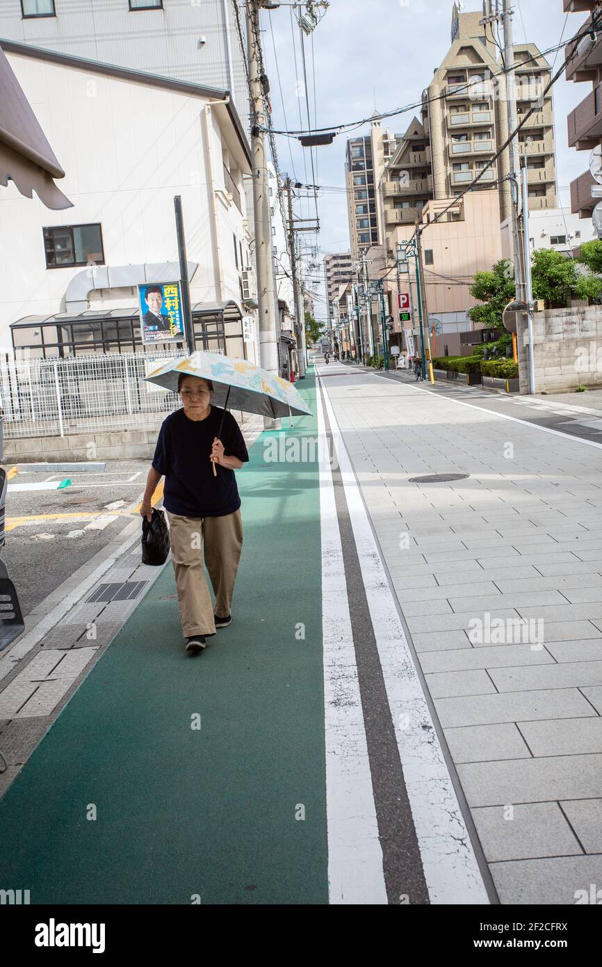 Donna singola con ombrello in strada, Akashi, prefettura di Hyogo, Giappone. Foto Stock