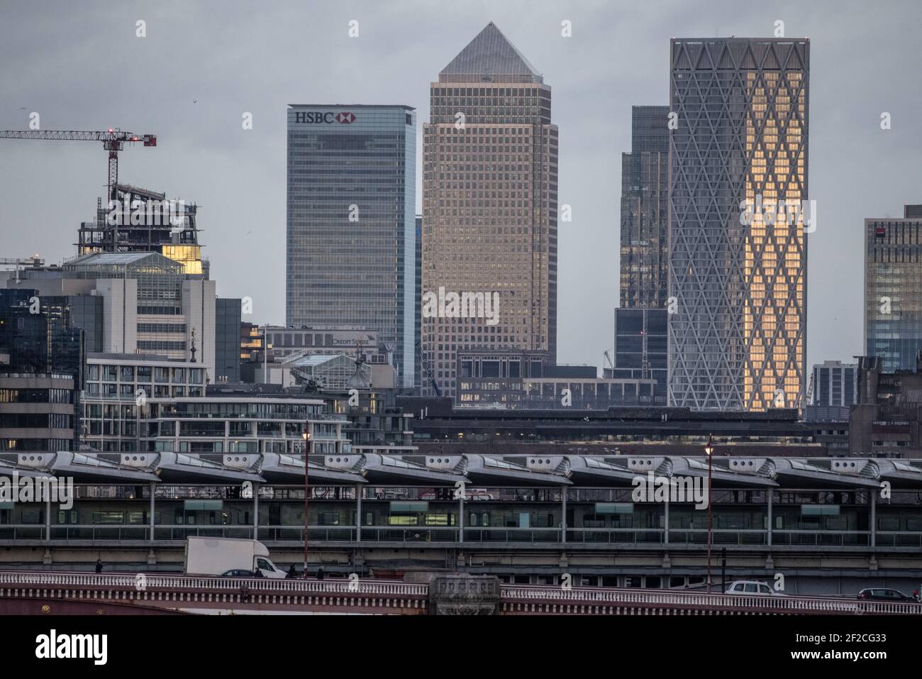 Skyline di Londra con grattacieli, tra cui Canary Wharf, in lontananza dalla stazione ferroviaria di Blackfriers nella città di Londra, in prima serata invernale. Foto Stock