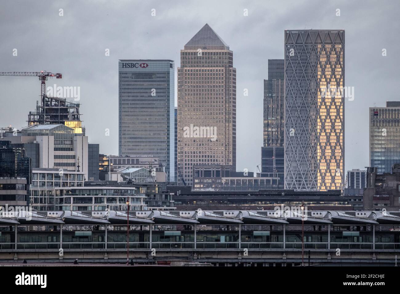 Skyline di Londra con grattacieli, tra cui Canary Wharf, in lontananza dalla stazione ferroviaria di Blackfriers nella città di Londra, in prima serata invernale. Foto Stock