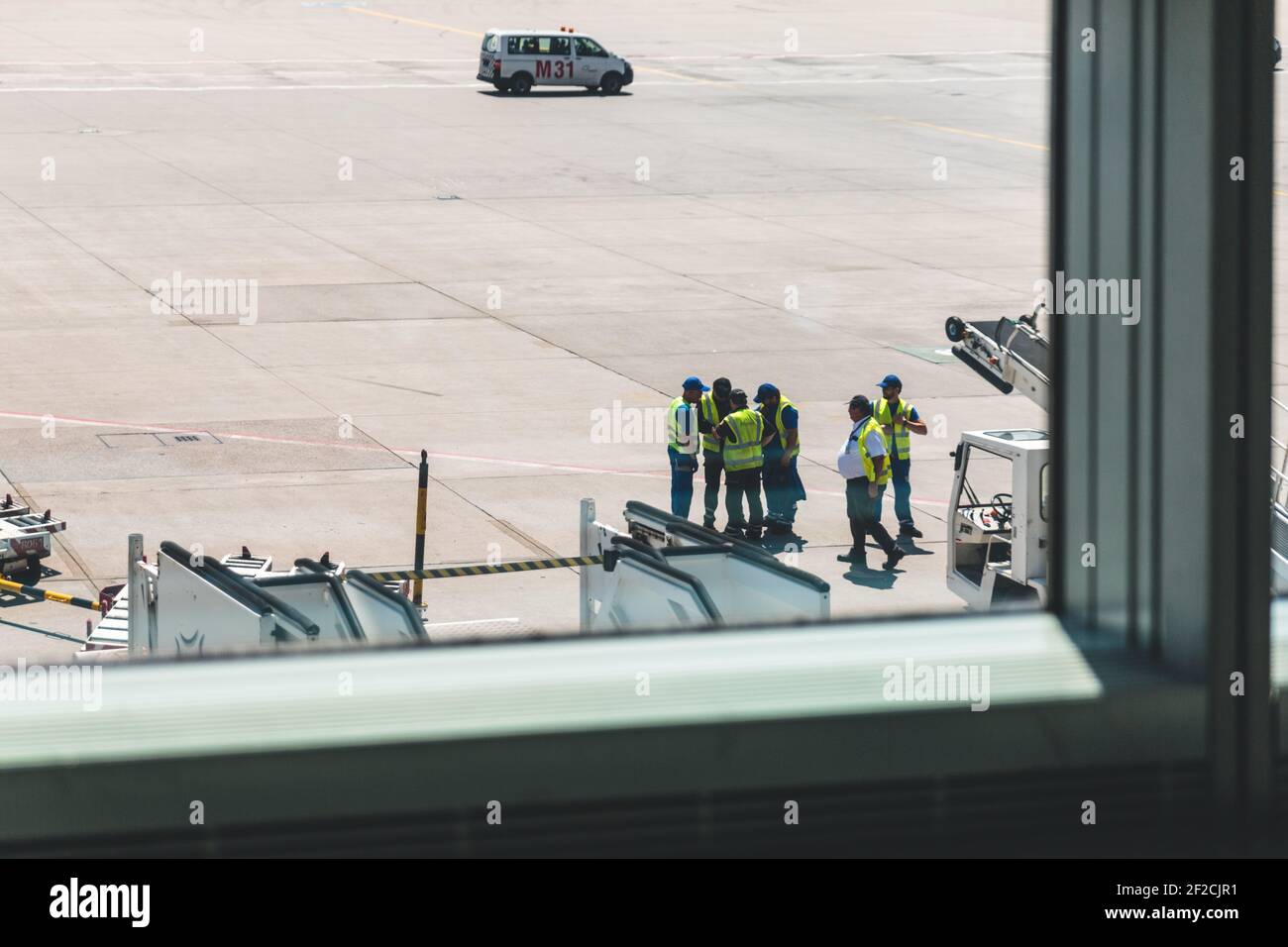 Gruppo di lavoratori di porti aerei in piedi in piena luce del sole visto attraverso una finestra Foto Stock
