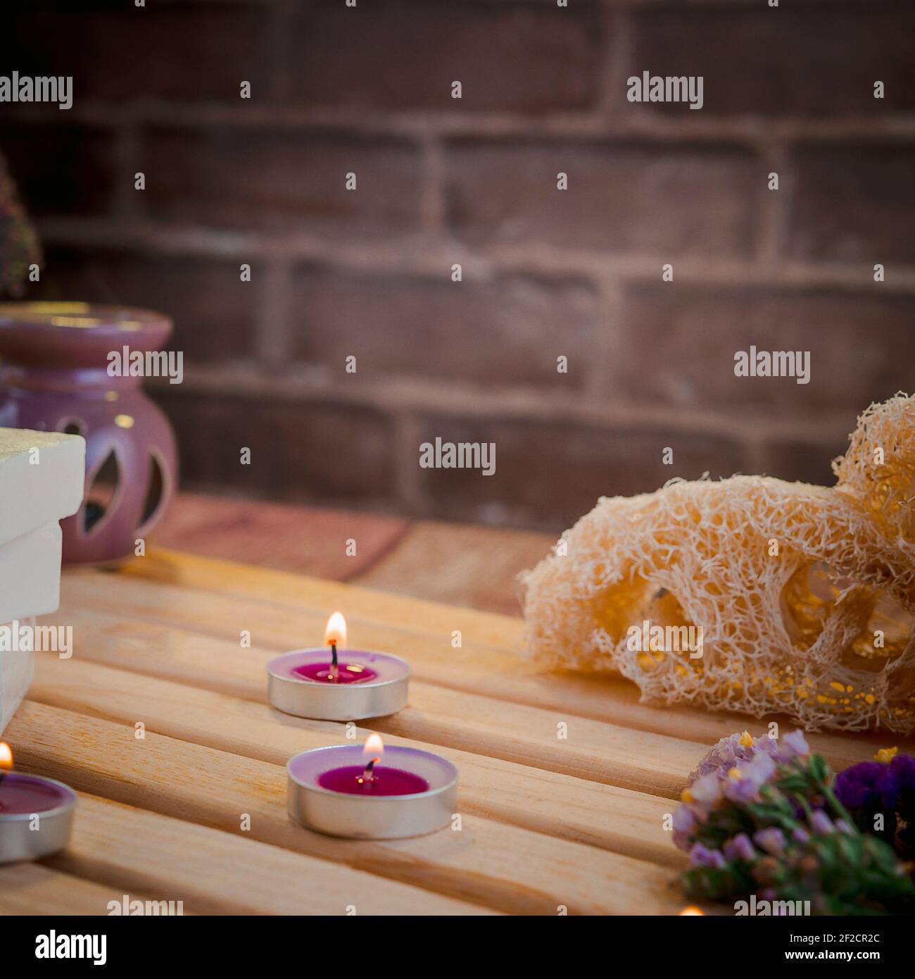 Bella composizione termale con saponi naturali con candele profumate e accessori da bagno in un ambiente romantico per un concetto di pulizia. Foto Stock