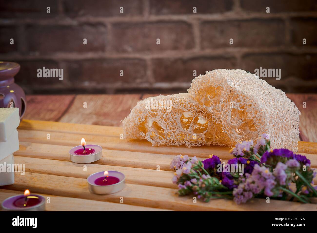 Bella composizione termale con saponi naturali con candele profumate e accessori da bagno in un ambiente romantico per un concetto di pulizia. Foto Stock