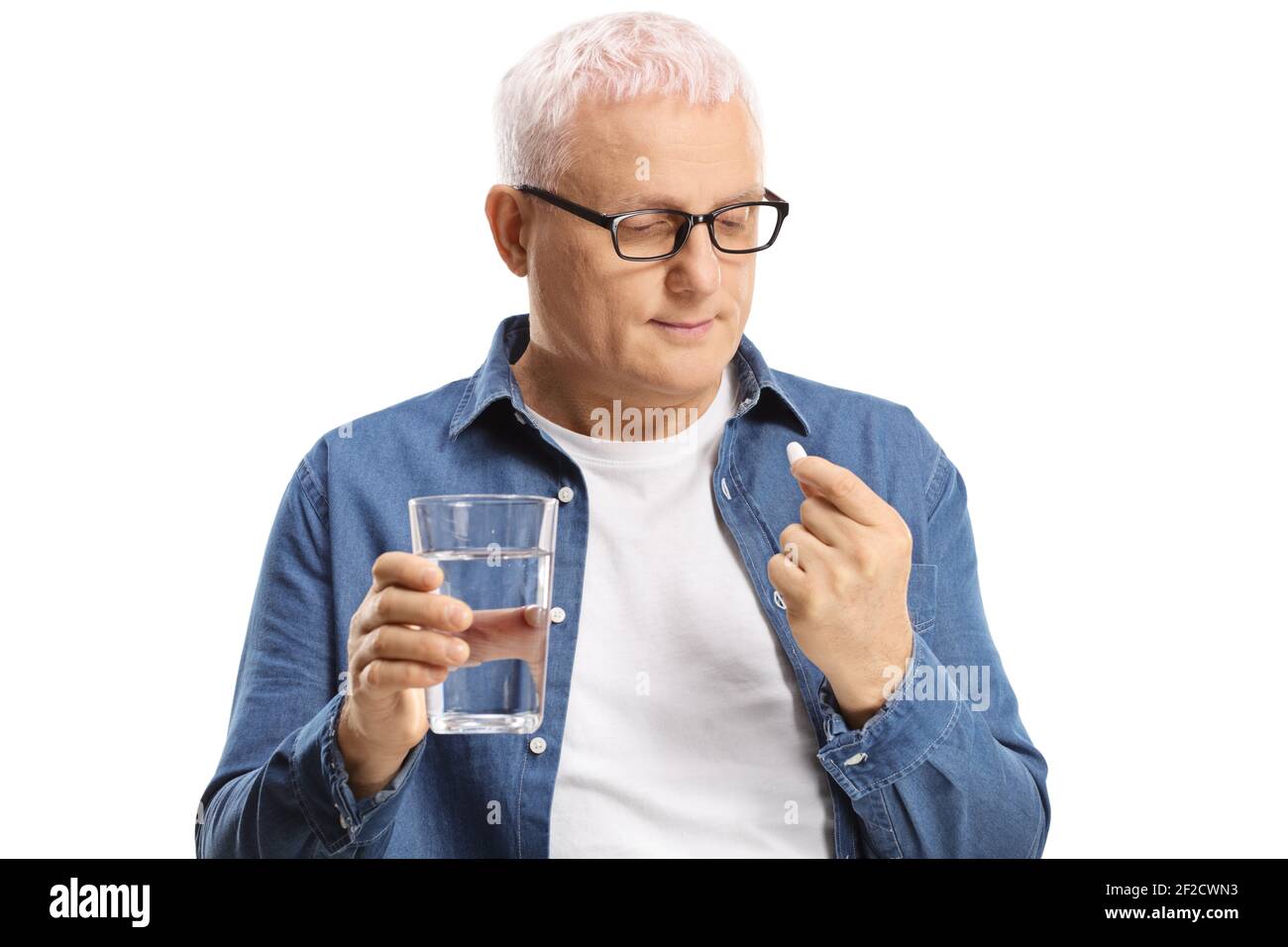 Uomo maturo che tiene una pillola e un bicchiere d'acqua isolato su sfondo bianco Foto Stock