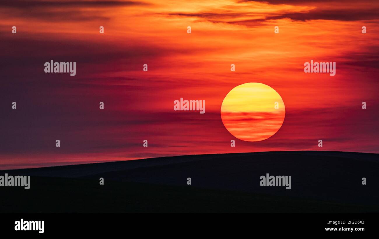 Impostazione del sole come palla rossa dalla polvere creata dall'agricoltura Attività nella Regione Palouse dello Stato di Washington Orientale Foto Stock