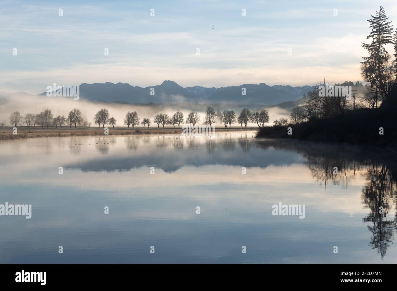 Il lago Sikes si riflette come uno specchio in una mattina tranquilla Sotto i cieli blu pastello nella Valle Snoqualmie del Re Contea di Washington occidentale Foto Stock