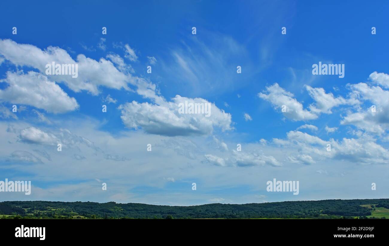 Bel paesaggio nuvoloso su una campagna boscosa collinare in bella giornata estiva, cumulo e circo nuvole bianche, cielo blu brillante Foto Stock