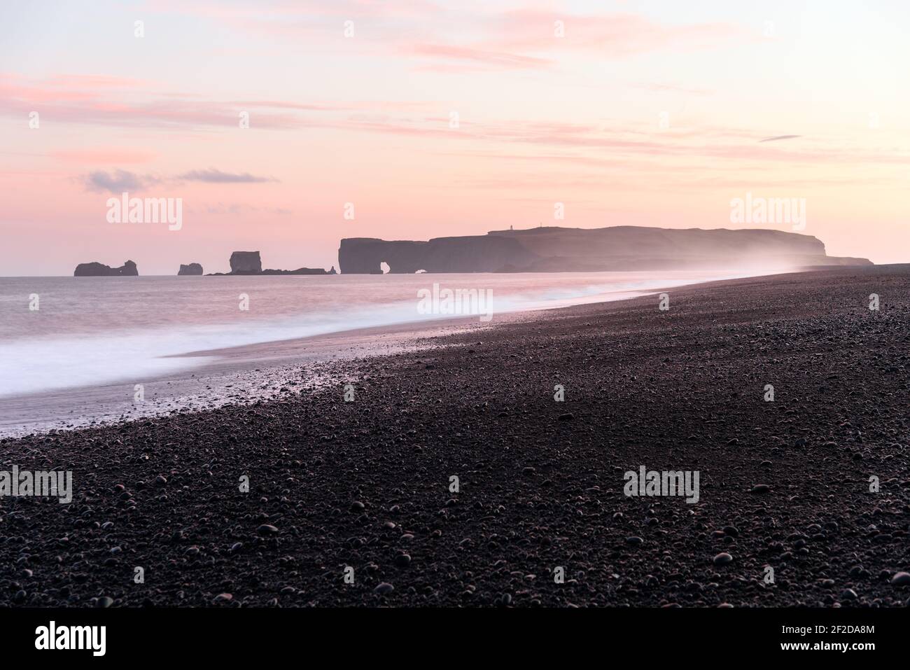 Magnifica spiaggia vulcanica deserta in Islanda sotto una bella rosa cielo in luce di mezzanotte in estate Foto Stock