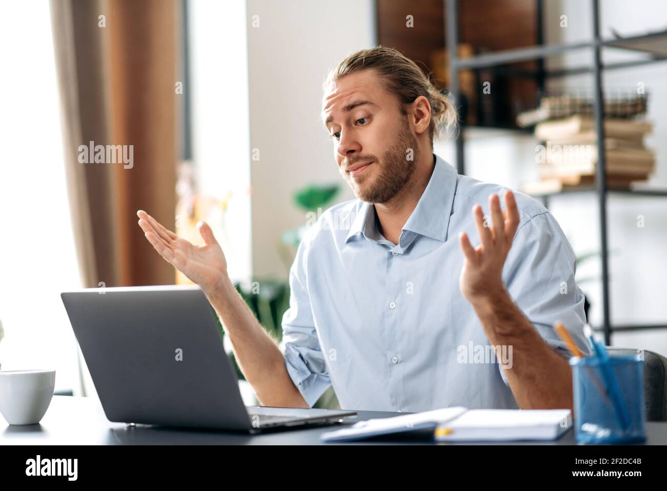 Infastidito caucasico busy business guy che guarda un portatile in confusione, ha ricevuto notizie inaspettate, ha fallito un accordo, grida, gesturing con le mani, seduto alla scrivania dell'ufficio di casa Foto Stock
