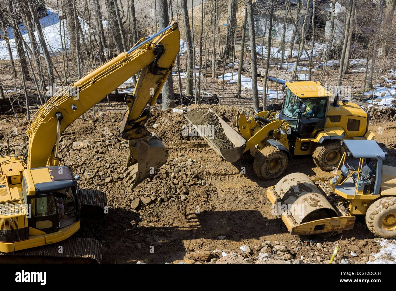 In costruzione di una nuova strada asfaltata. Gli escavatori, le livellatrici e i rulli stradali lavorano sulla nuova costruzione stradale Foto Stock