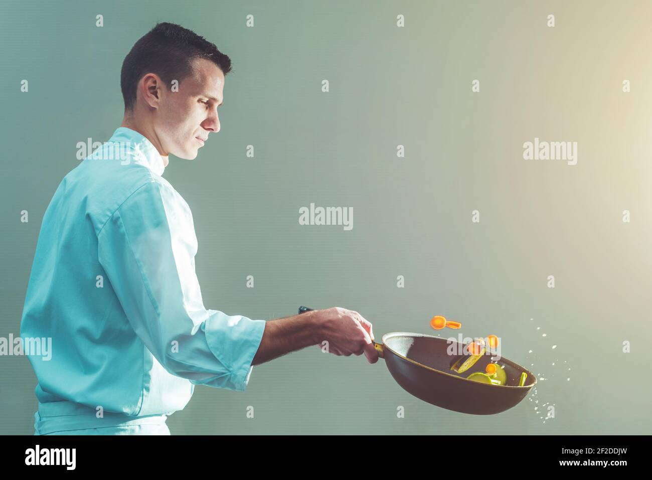 Giovane chef professionista che prepara e flipping le verdure in una padella, concetto di cuoco professionale con spazio per la copia Foto Stock