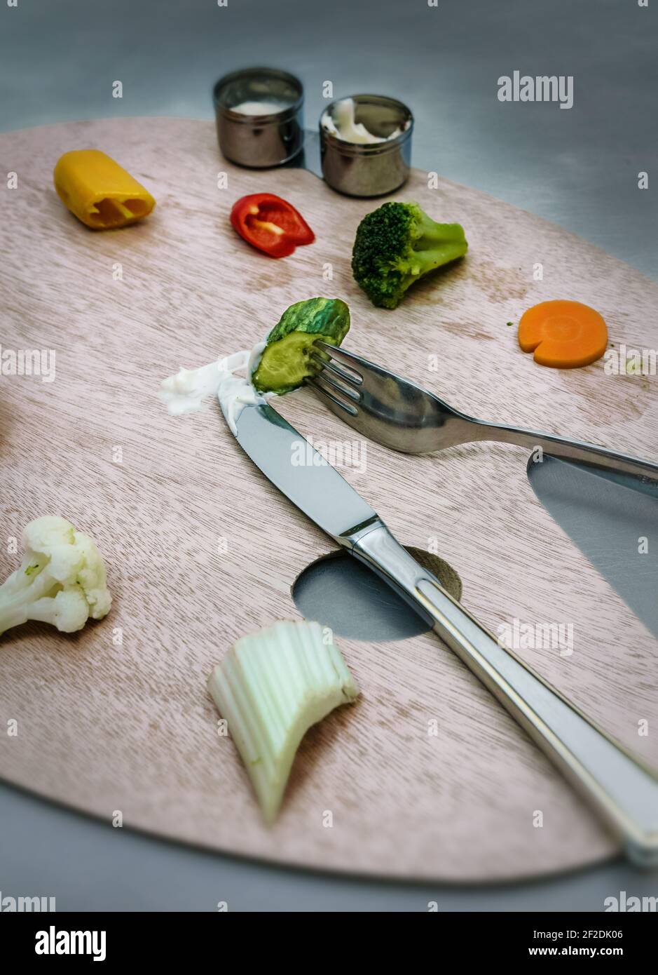 Artista tavolozza di legno su cui sono collocate le verdure. Nelle tazze c'è un bagno di verdure. Un coltello e una forcella. Foto Stock