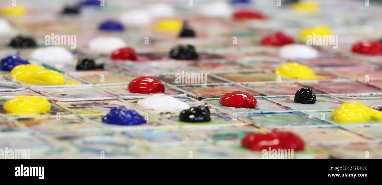 Una vista ravvicinata delle tavolozze di pittura allestite per le lezioni d'arte a scuola. Colori primari e secondari organizzati su una t Foto Stock