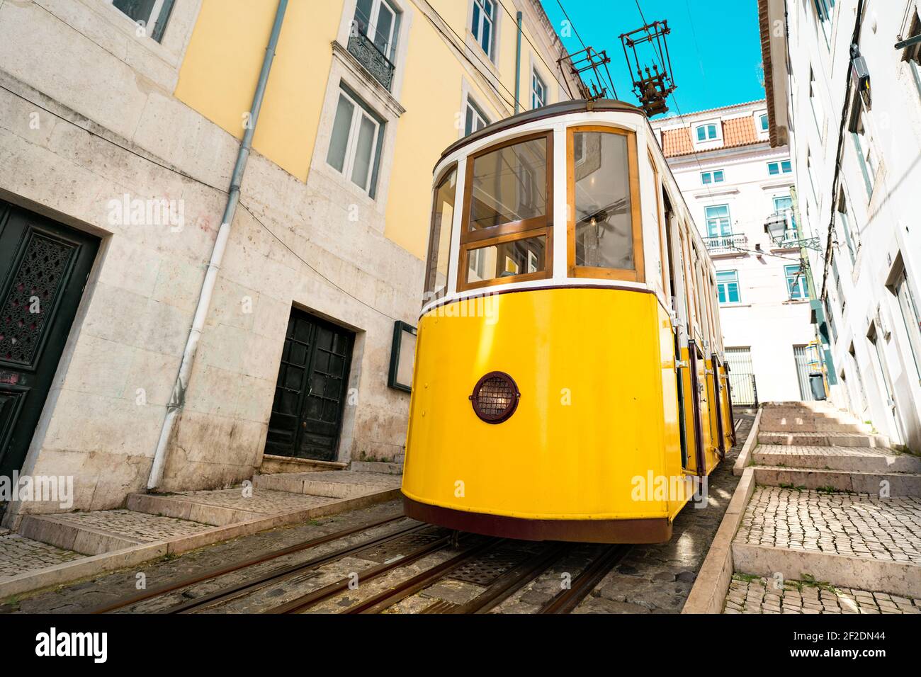 Vista frontale della famosa funicolare gialla retrò di Bica nelle strette strade della città vecchia di Lisbona, Portogallo Foto Stock