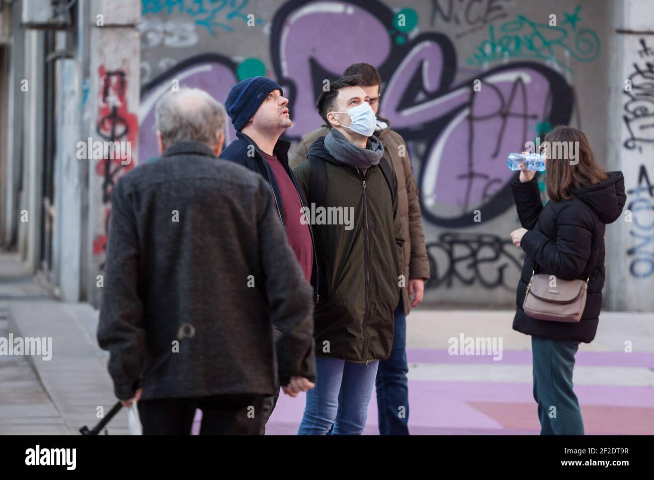 BELGRADO, SERBIA - 21 FEBBRAIO 2021: Giovane uomo che indossa una maschera respiratoria che guarda sopra il cielo nella strada di Belgrado, durante il coronav Foto Stock
