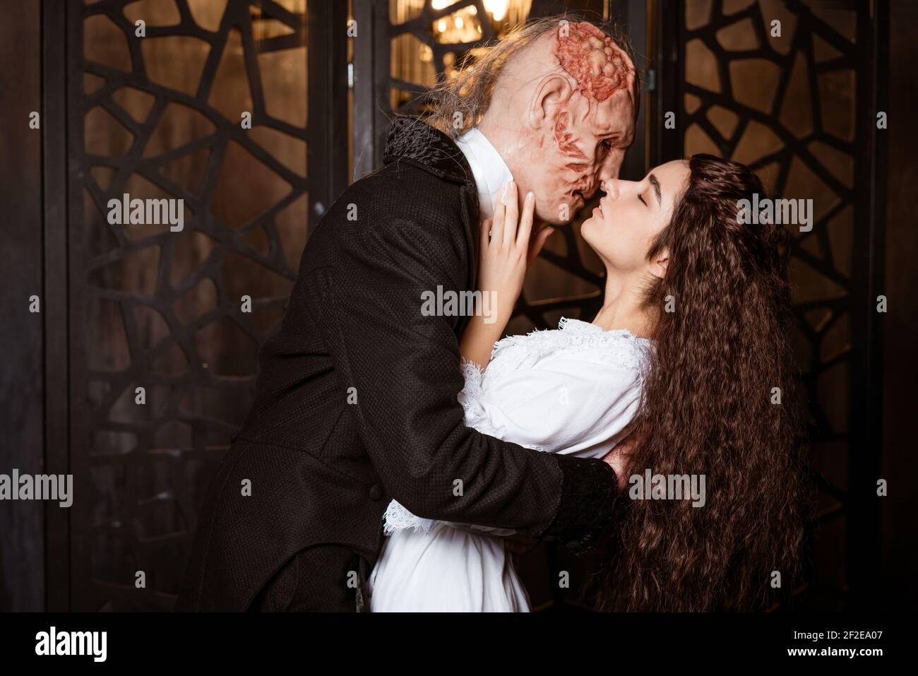 un brutto uomo in un cappotto bacia un giovane bello brunette in un peignoir bianco - cosplay per il musical Il Fantasma dell'Opera Foto Stock