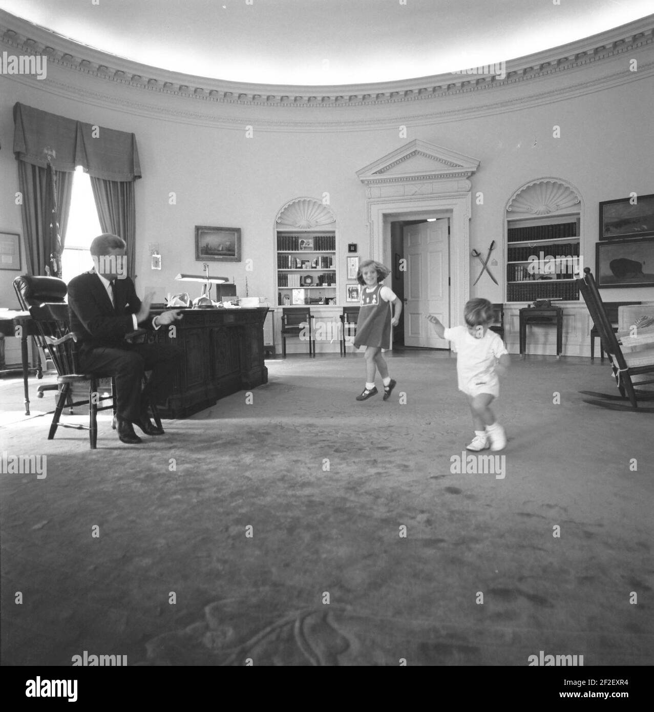 Il presidente John F. Kennedy Claps mentre i suoi bambini Caroline e John, Jr. Dance nell'ufficio ovale, Casa Bianca, Washington, DC. Foto Stock