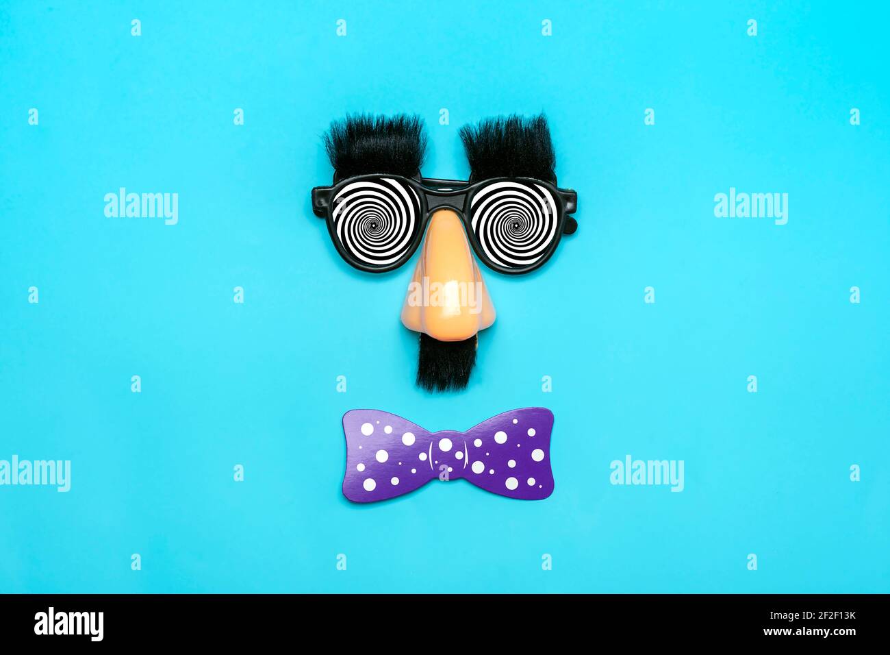 Faccia divertente - occhiali falsi, naso e baffi, confetti, paillettes su sfondo blu Happy fools Day Concept 1st April party Holiday card Foto Stock