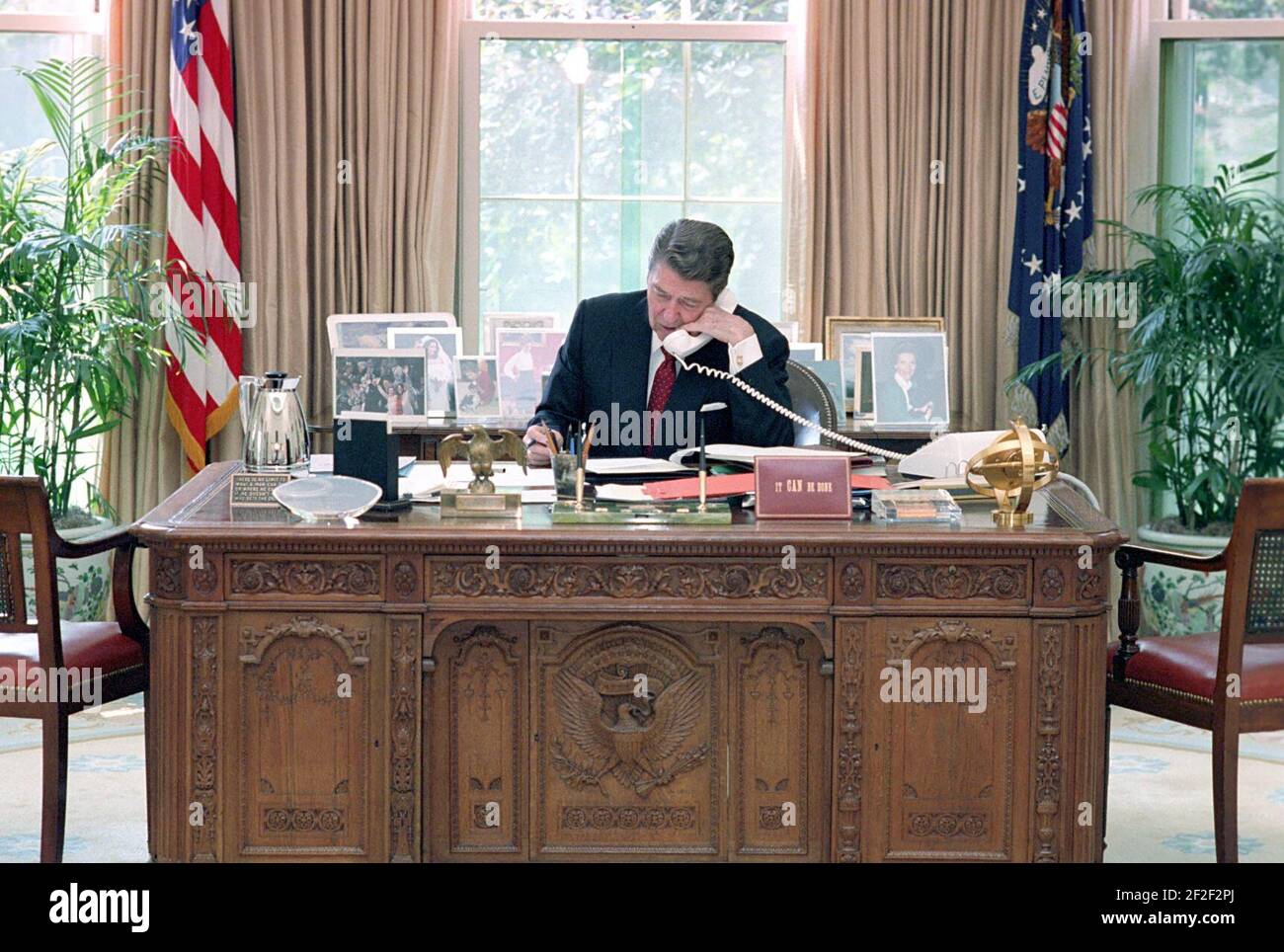 Il presidente Ronald Reagan durante una telefonata al membro del Congresso per aver fatto pressione sulla sua scrivania nell'ufficio ovale. Foto Stock