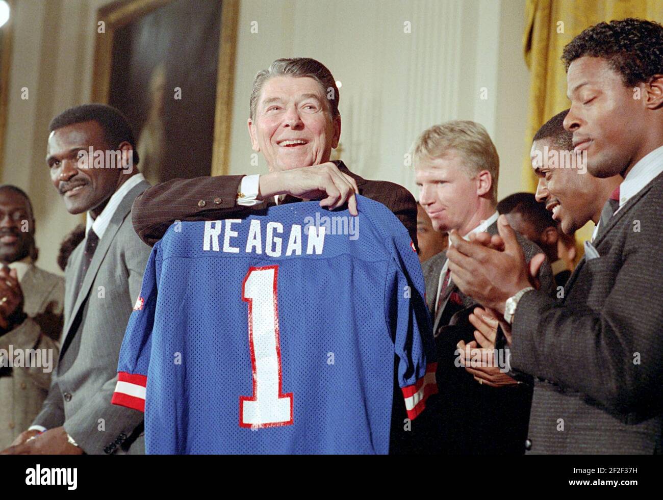 Il presidente Ronald Reagan riceve un regalo durante una foto con la squadra di football dei New York Giants. Foto Stock