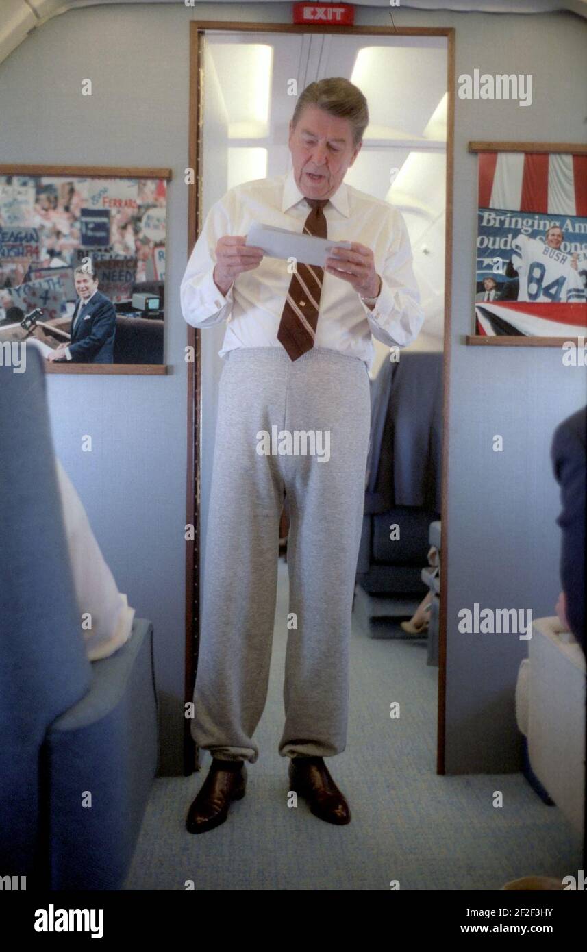 Il presidente Ronald Reagan indossa pantaloni che parlano con il personale a bordo dell'Air Force One in un viaggio in Iowa. Foto Stock