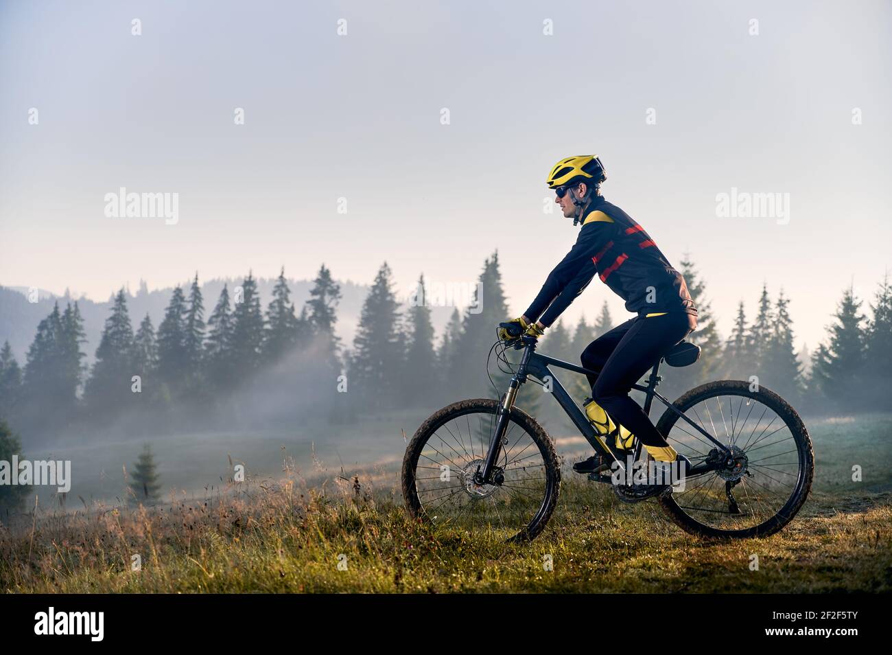 Giovane uomo in bicicletta in montagna al mattino presto Foto Stock