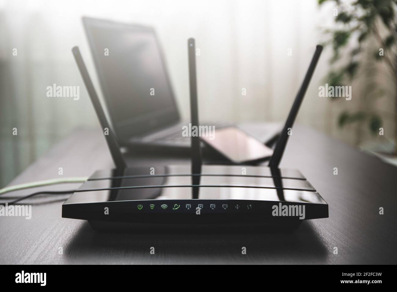 Router WI-FI connesso a Internet sul tavolo e sul computer portatile sullo sfondo Foto Stock