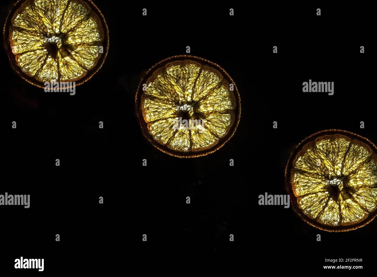 Fette arancioni essiccate su sfondo nero, primo piano, isolate, retroilluminazione Foto Stock